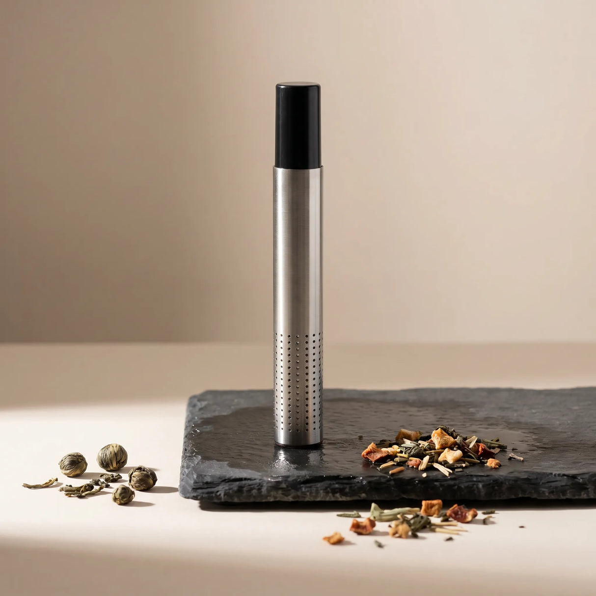 Premium stainless steel tea infuser steeping in a white ceramic mug with steam rising, loose tea leaves scattered on a wooden table